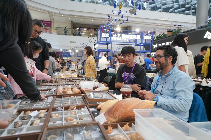 Vendors talk with customers during a shell product promotion event at a mall in Chaoyang District of Beijing, capital of China, Oct. 2, 2024. (Xinhua/Wu Qinghao)