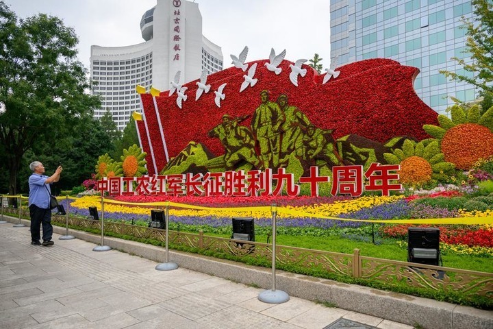 A senior takes pictures of a set of floral decorations at Jianguomen along Chang'an Avenue in Beijing, capital of China, Sept. 25, 2026. Floral decorations have been set up along the Chang'an Avenue in Beijing ahead of China's National Day holidays. (Xinhua/Hu Jingwen)