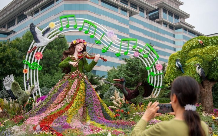 A woman takes pictures of a set of floral decorations at Xidan area along Chang'an Avenue in Beijing, capital of China, Sept. 25, 2026. Floral decorations have been set up along the Chang'an Avenue in Beijing ahead of China's National Day holidays. (Photo by Zhang Youlin/Xinhua)