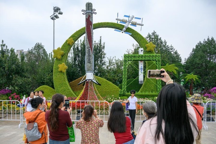 People pose for photos in front of a set of floral decorations at Dongdan area along Chang'an Avenue in Beijing, capital of China, Sept. 25, 2026. Floral decorations have been set up along the Chang'an Avenue in Beijing ahead of China's National Day holidays. (Xinhua/Hu Jingwen)